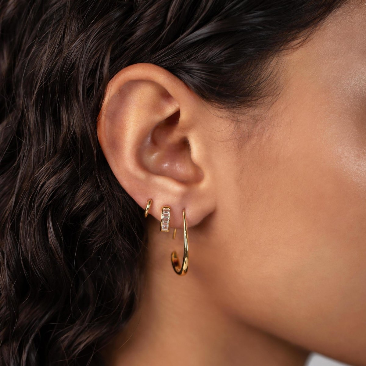 Gold vermeil teardrop hoop earring, shown on a model's lobe below baguette and ring details