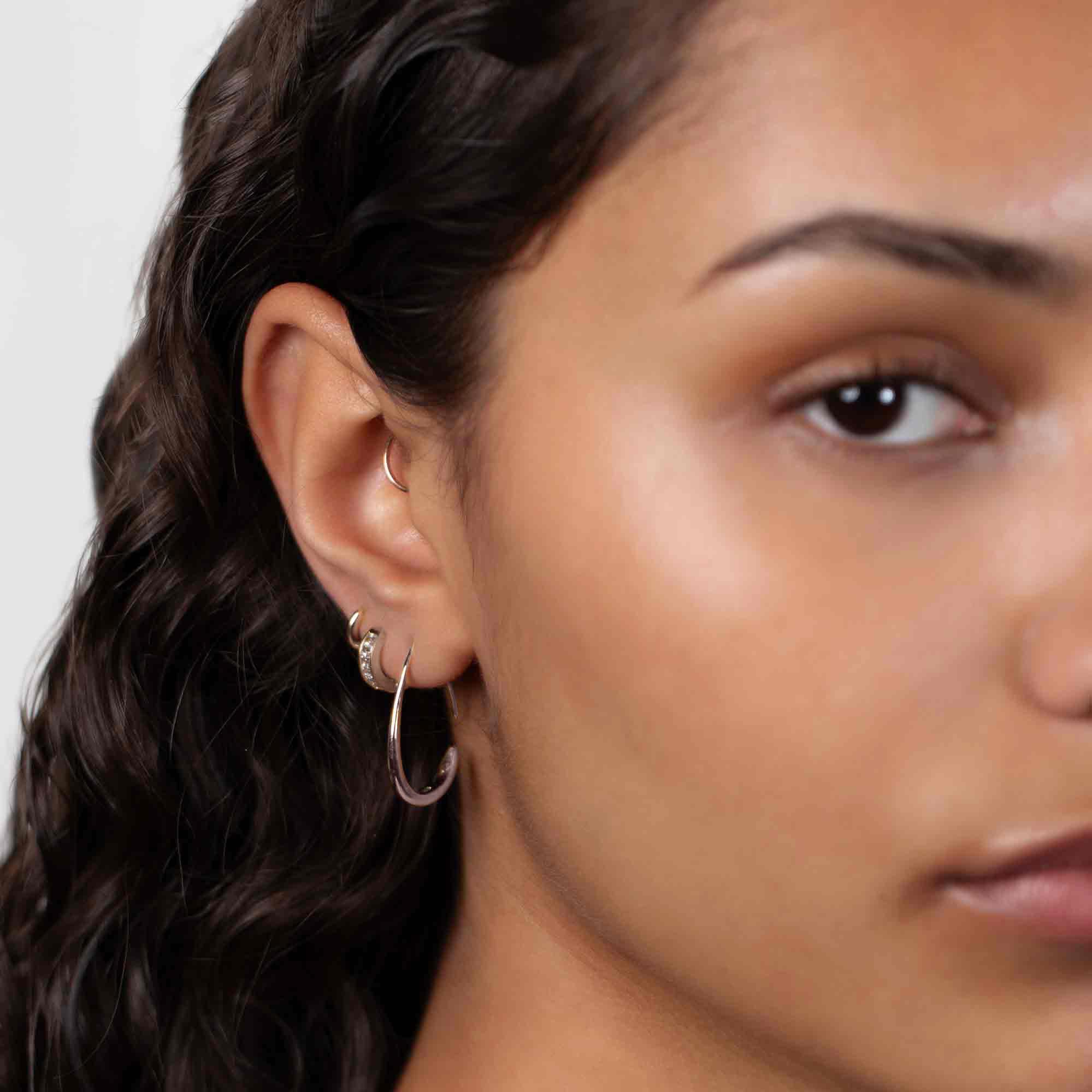 Sterling silver teardrop hoop earring, shown on a model's lobe in a layered ear look