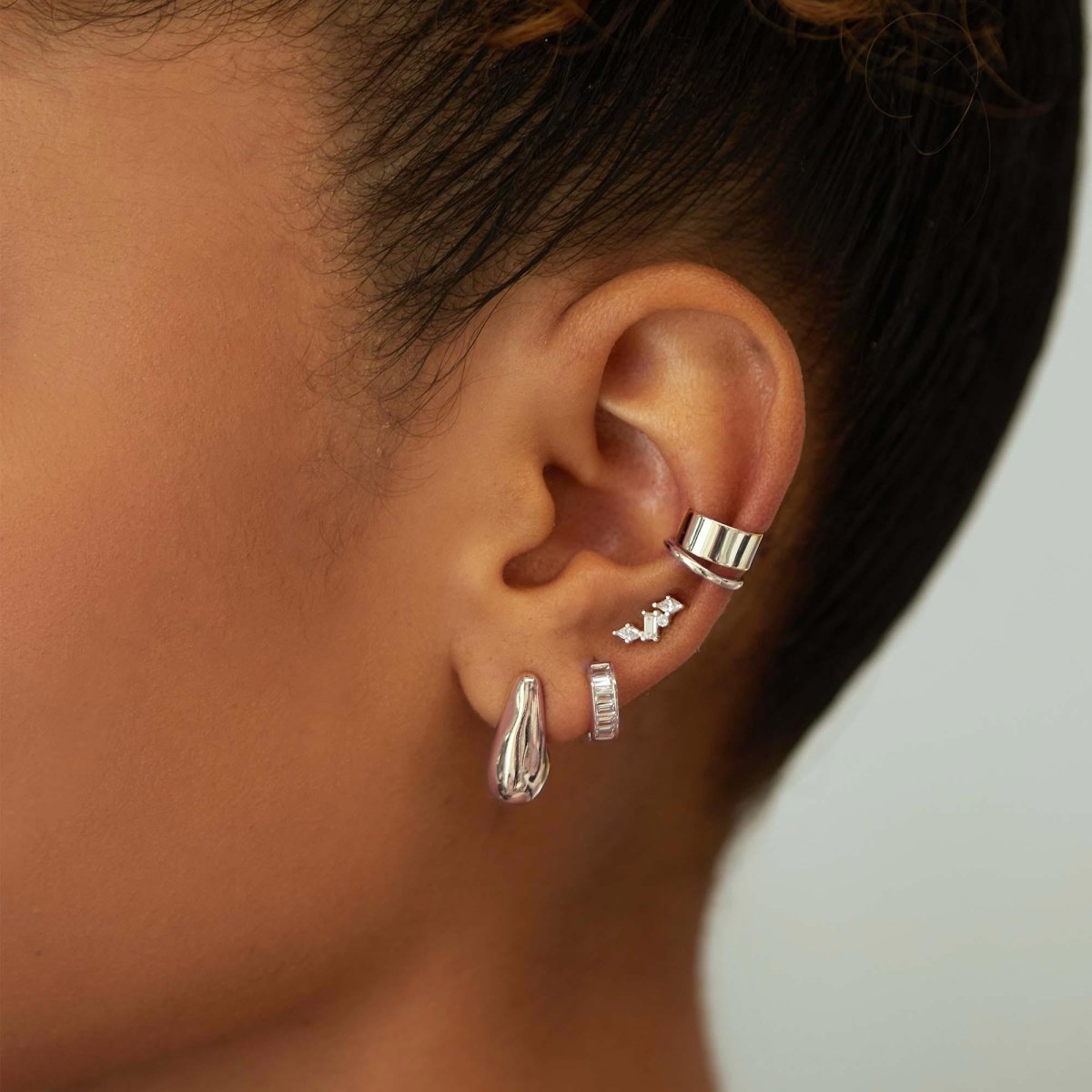 Sterling silver scattered cluster studs with white zirconia stones, shown on a model's lobe