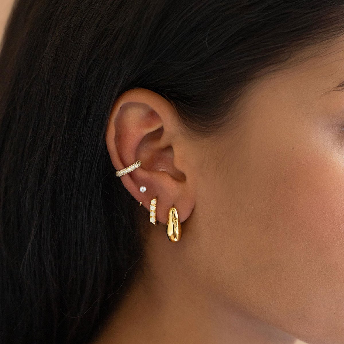 Gold pearl stud, ear cuff and chunky hoops styled in an ear stack on a model