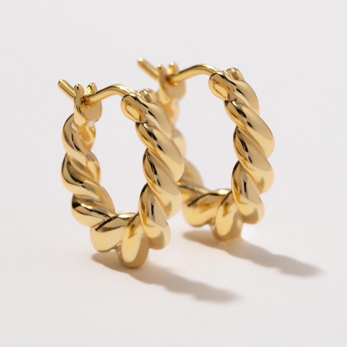 Pair of gold vermeil thick twisted rope huggie hoops shown loose on a cream background