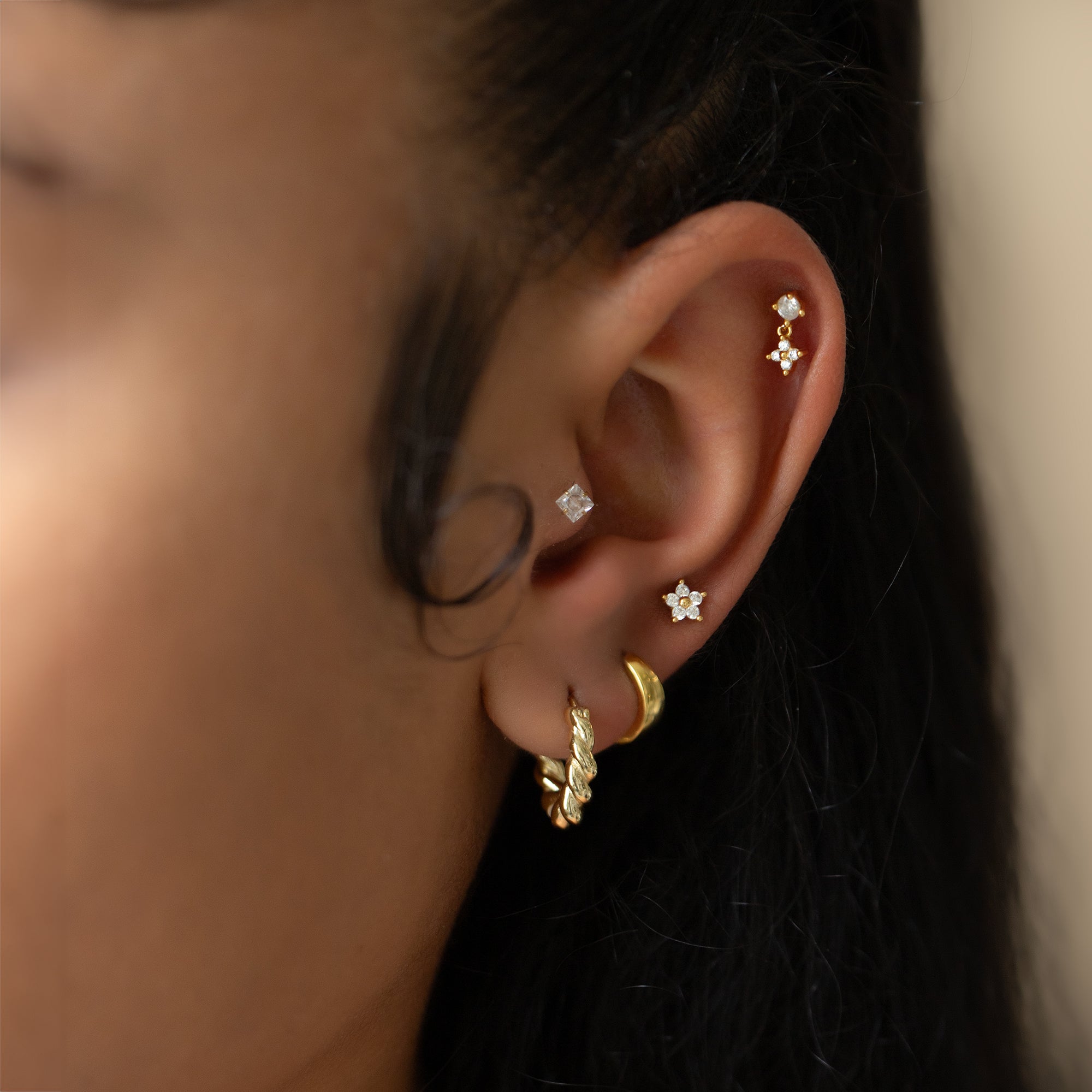 Gold vermeil flower flat back studs with clear white zirconia shown on a model's lobe and helix