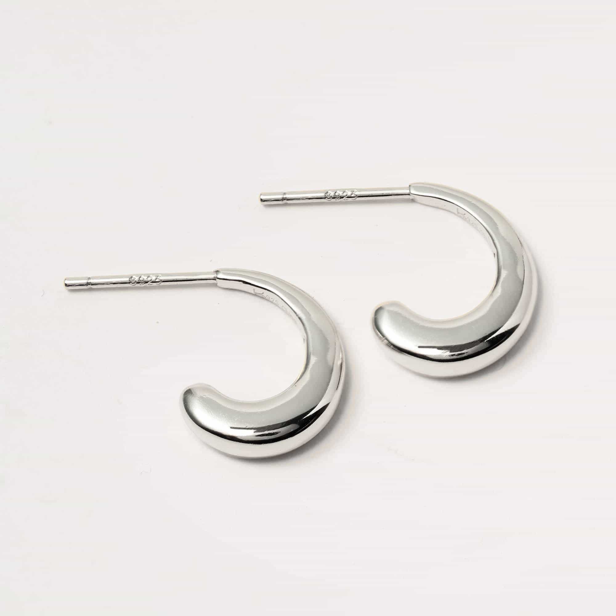 Sterling silver small J hoop earrings shown at an angle with stamped post backs, on a white background