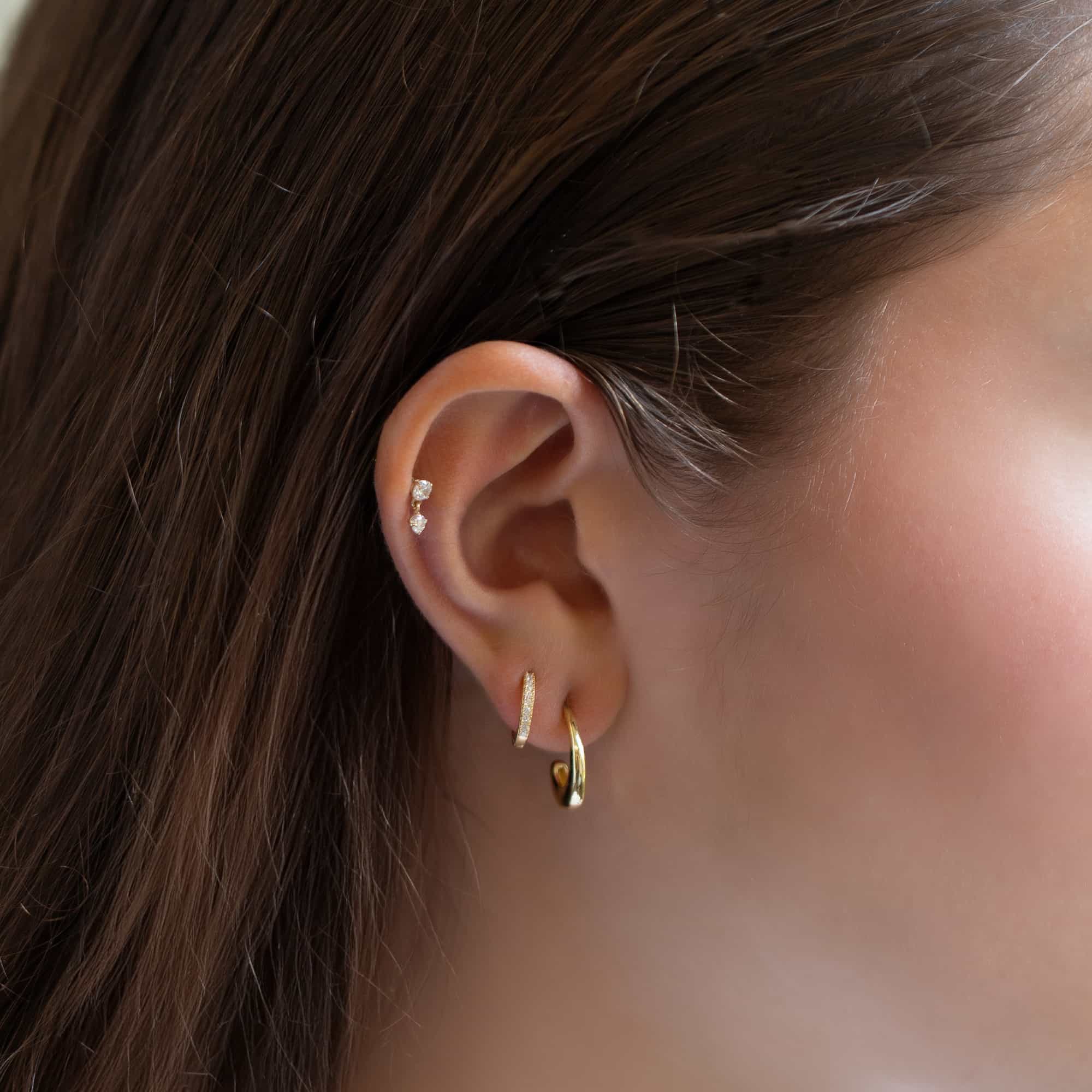 14K gold white zirconia dangle flat back stud shown in a helix piercing on a model's ear