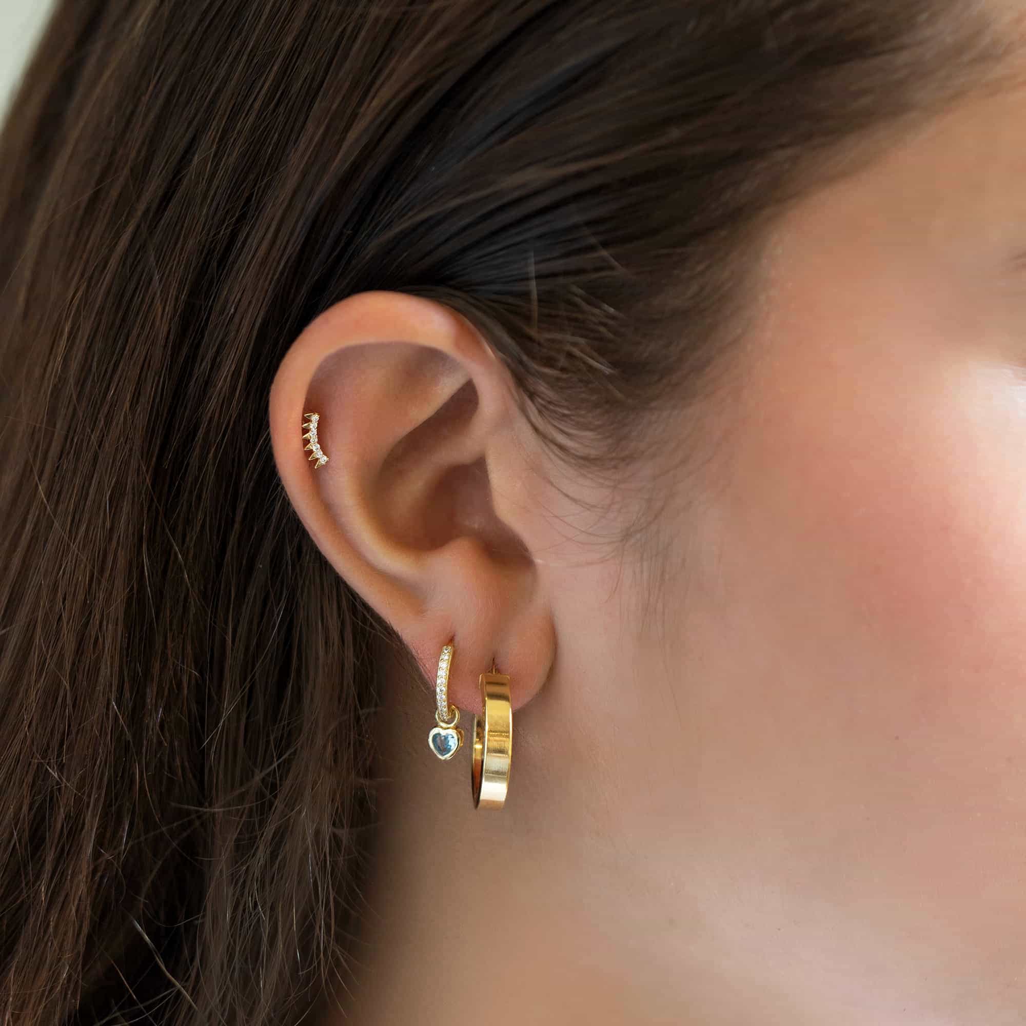 14K gold spike flat back stud with white zirconia shown in an upper-ear piercing on a model