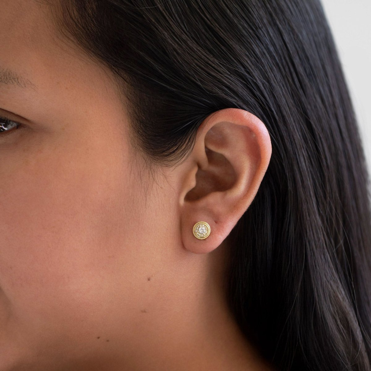 Gold vermeil white zirconia halo stud with roped border, shown on a model's lobe