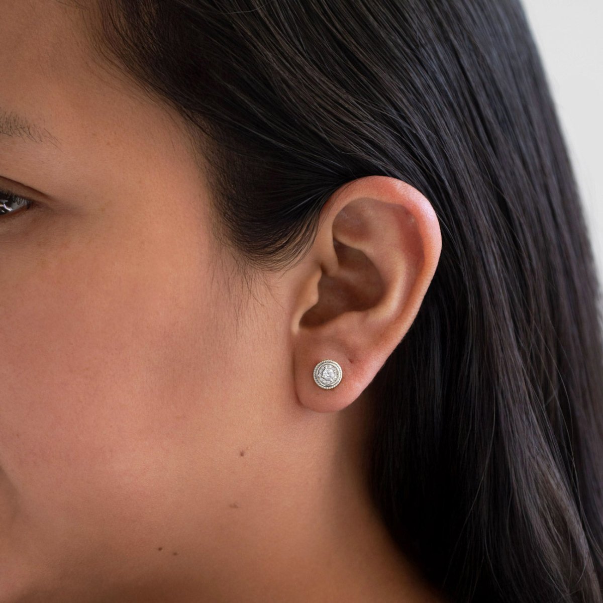 Sterling silver white zirconia halo stud with roped border, shown on a model's lobe