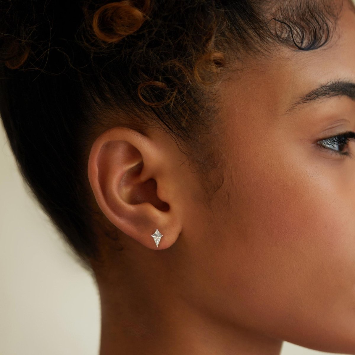 Sterling silver kite-shaped clear crystal stud shown close-up on a model's earlobe