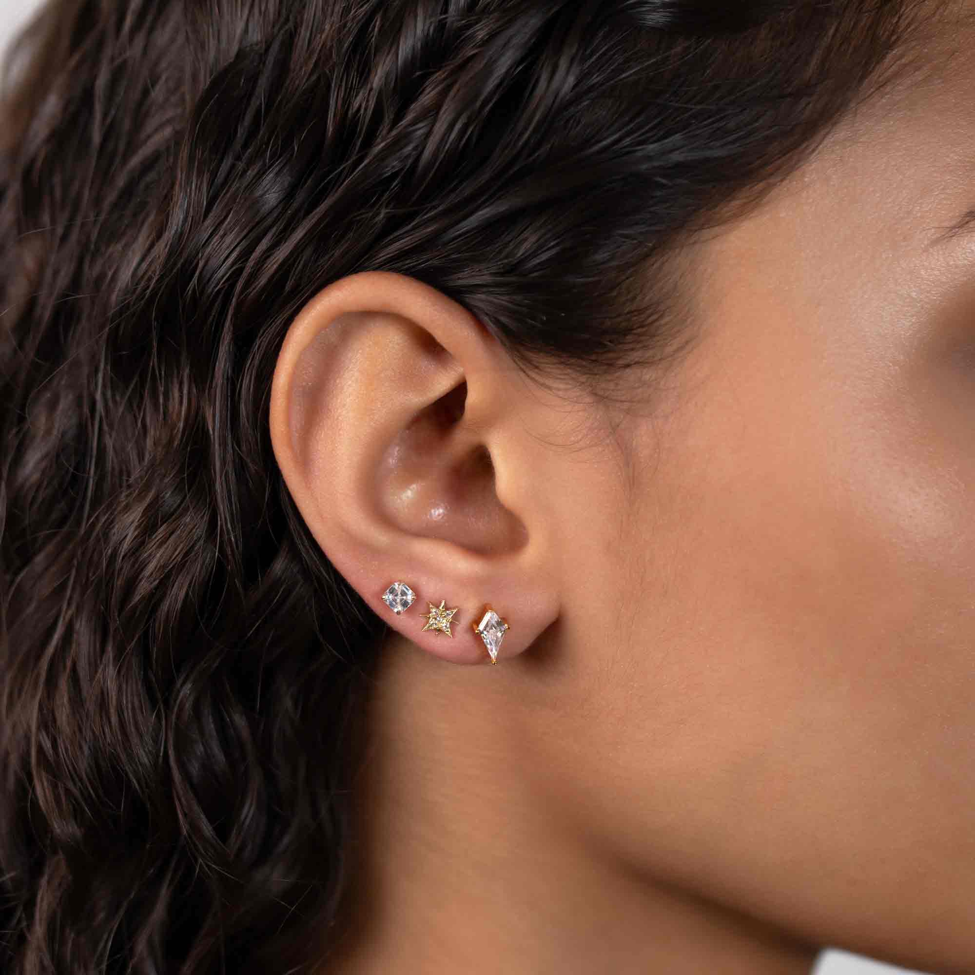 Gold vermeil kite-shaped clear crystal stud shown on a model's lower lobe in an ear stack
