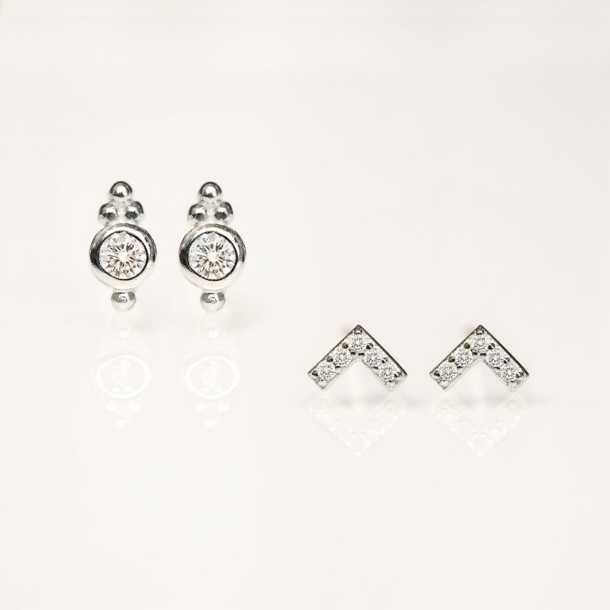 Sterling silver chevron stud and round clear-stone stud earrings, on a white background