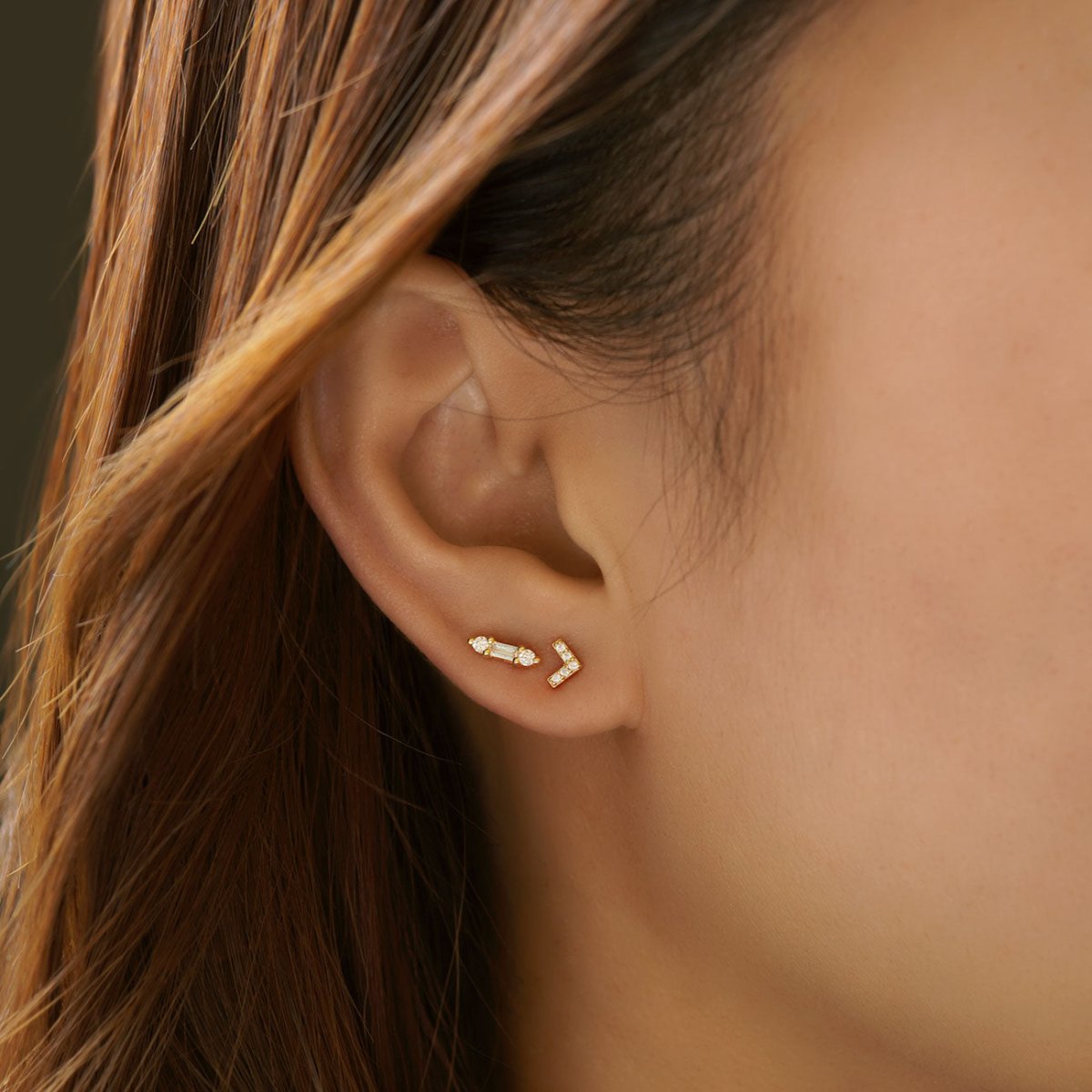 Gold vermeil baguette bar studs with clear stones, shown on a model's lobe in an ear stack