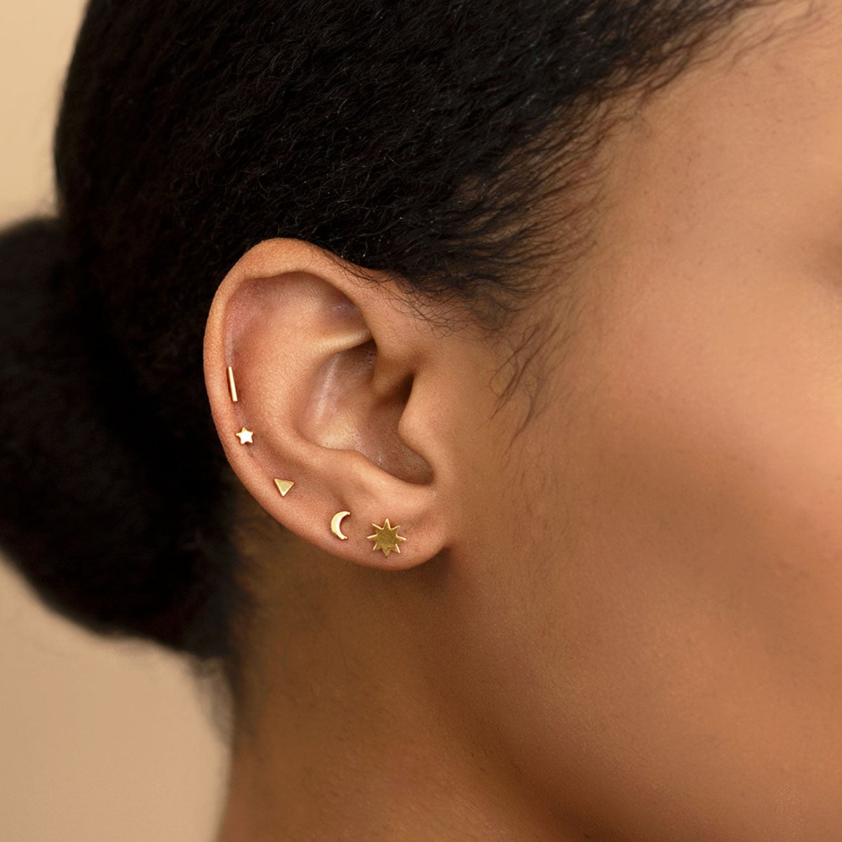 Gold vermeil tiny star and crescent moon studs shown on a model's ear, side profile view