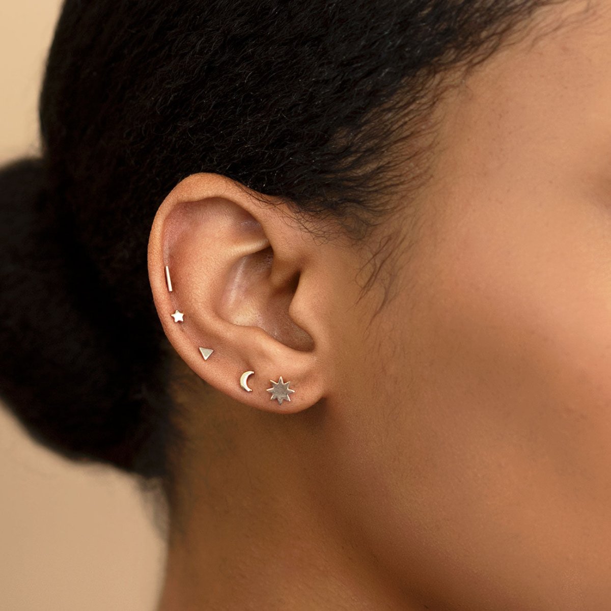 Sterling silver thin bar stud shown on a model's ear among star, moon and starburst studs
