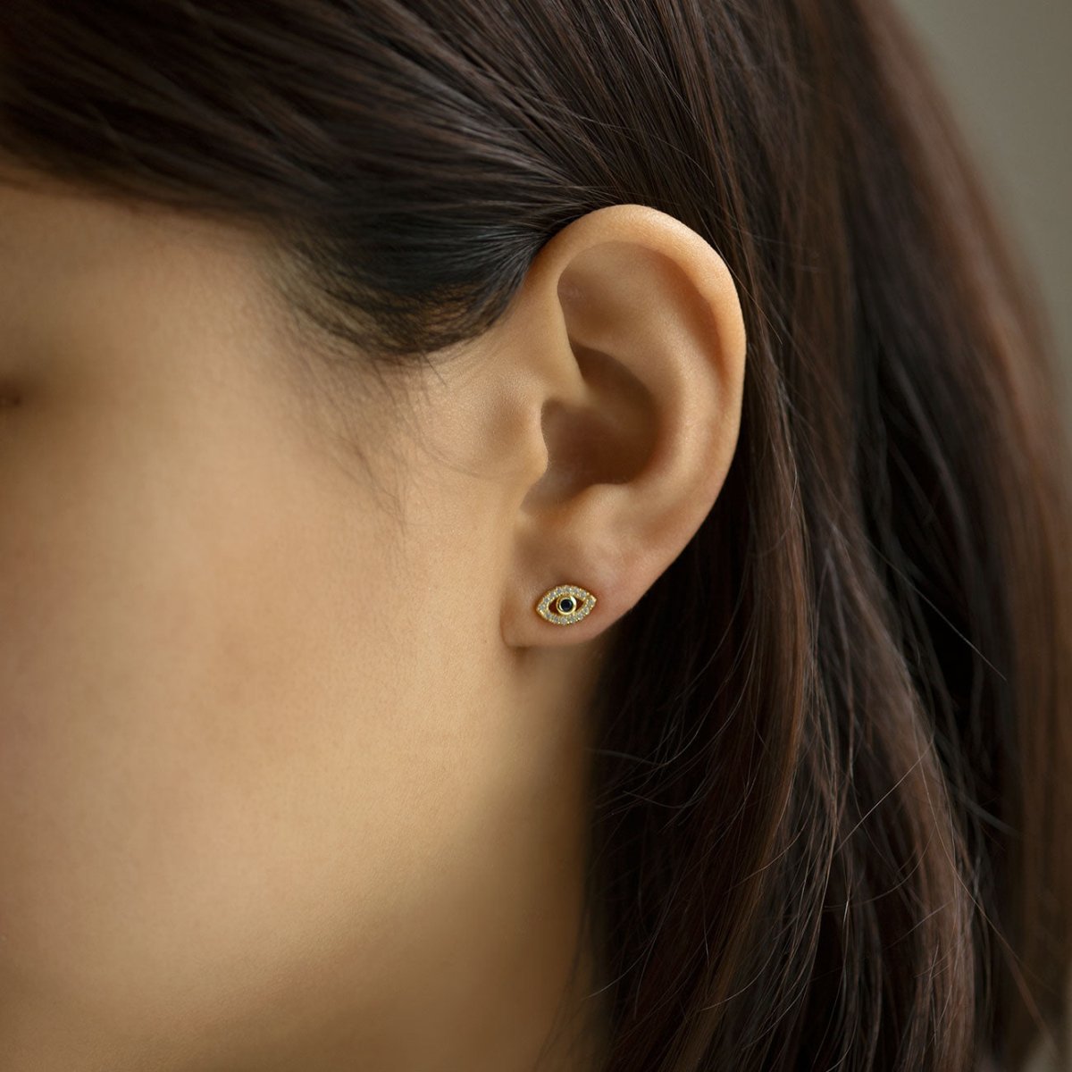 Gold vermeil evil eye stud with a blue sapphire center, shown on a model's lobe