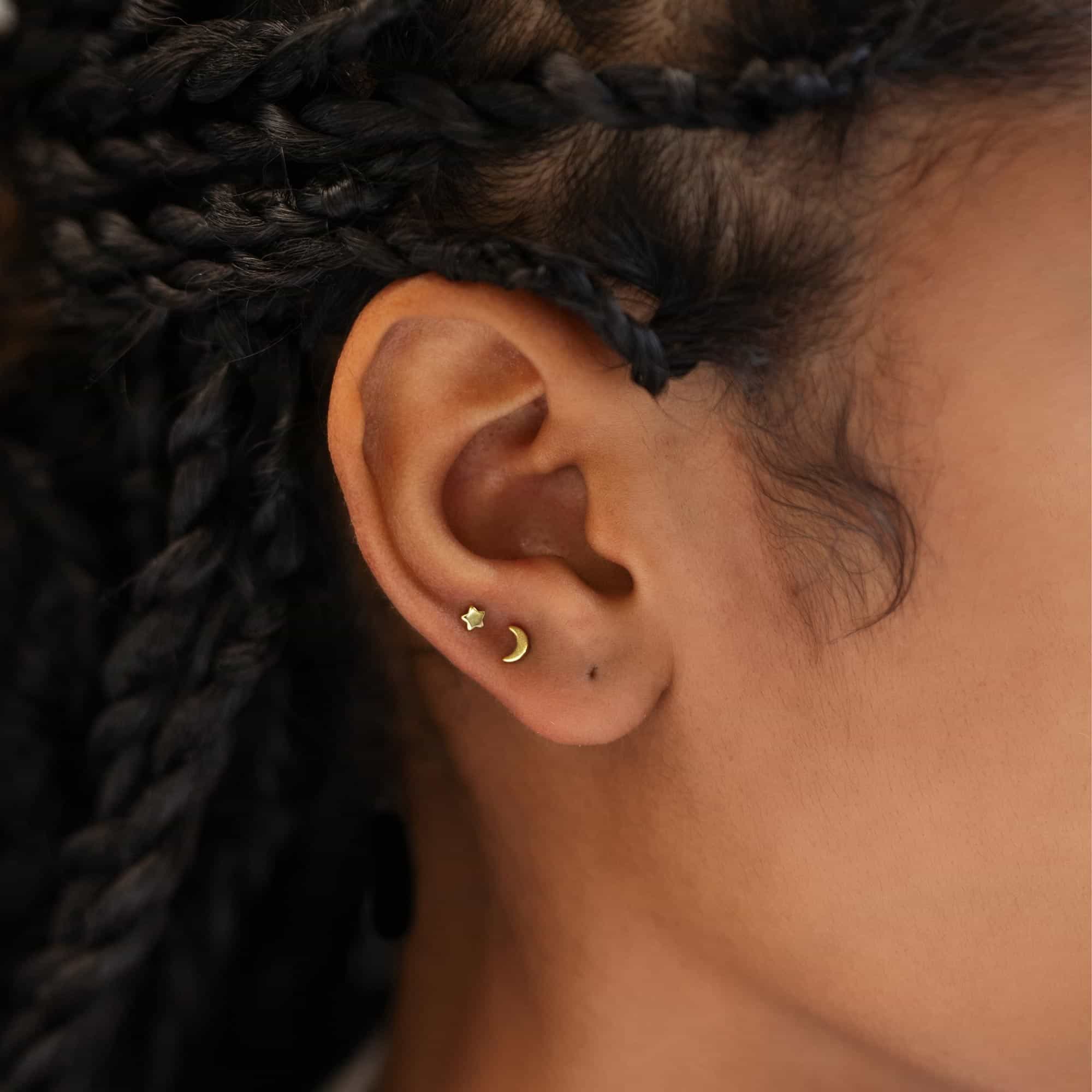 Gold vermeil tiny star and crescent moon studs shown on a model's upper ear lobe