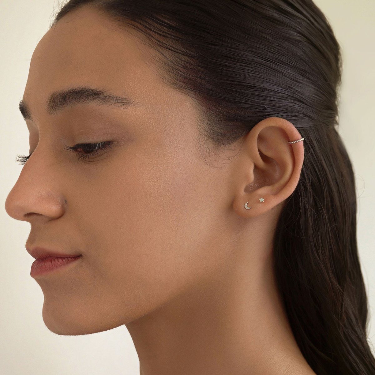 Sterling silver beaded ear cuff worn as an ear band, side profile on a model's ear