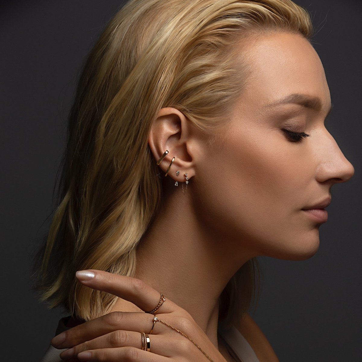 14K gold diamond drop chain earrings, shown on a model's ear in a layered ear stack