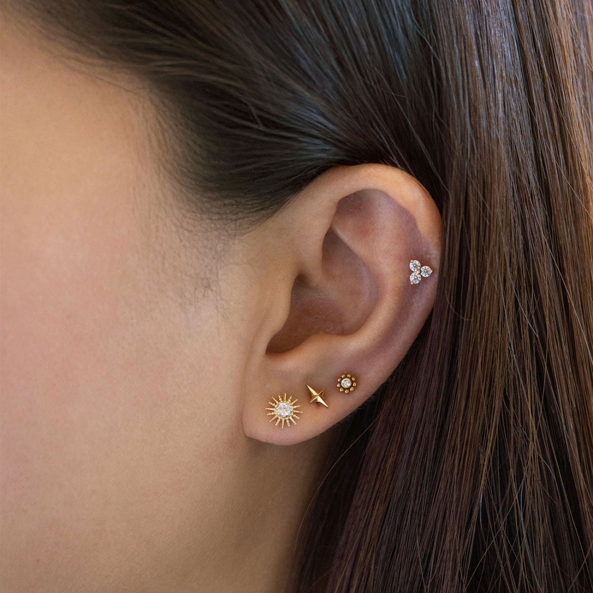 Gold star flat back stud styled with hoops on a model's ear