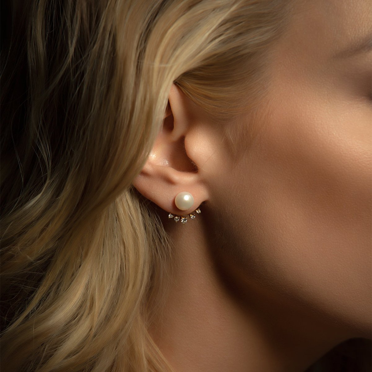 Gold vermeil pearl ear jacket studs with a crystal fan, shown close on a model's ear