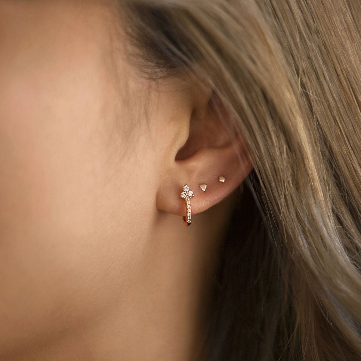 Rose gold vermeil tiny star stud shown on a model's ear in a gold lobe stud stack