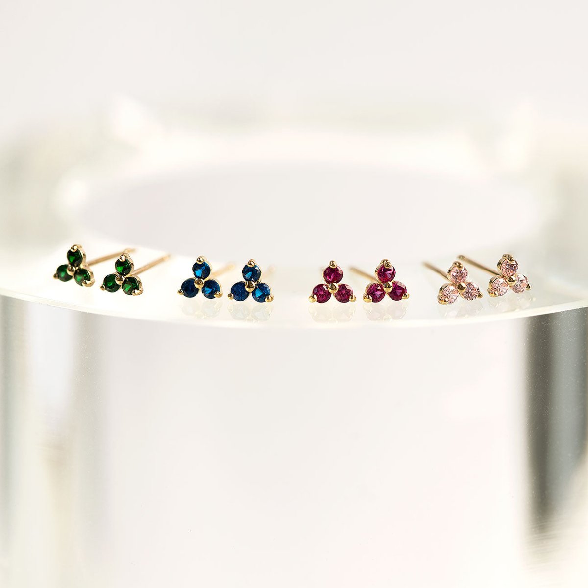 Close up of earrings featuring 14K Gold Gemstone Clover Studs Sapphire Blue Crystal and other gemstone colors 