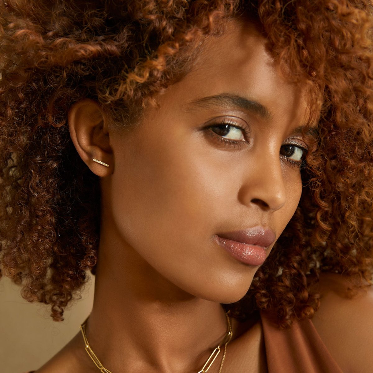Gold vermeil pave bar stud earring with clear stones, shown on a model's upper lobe