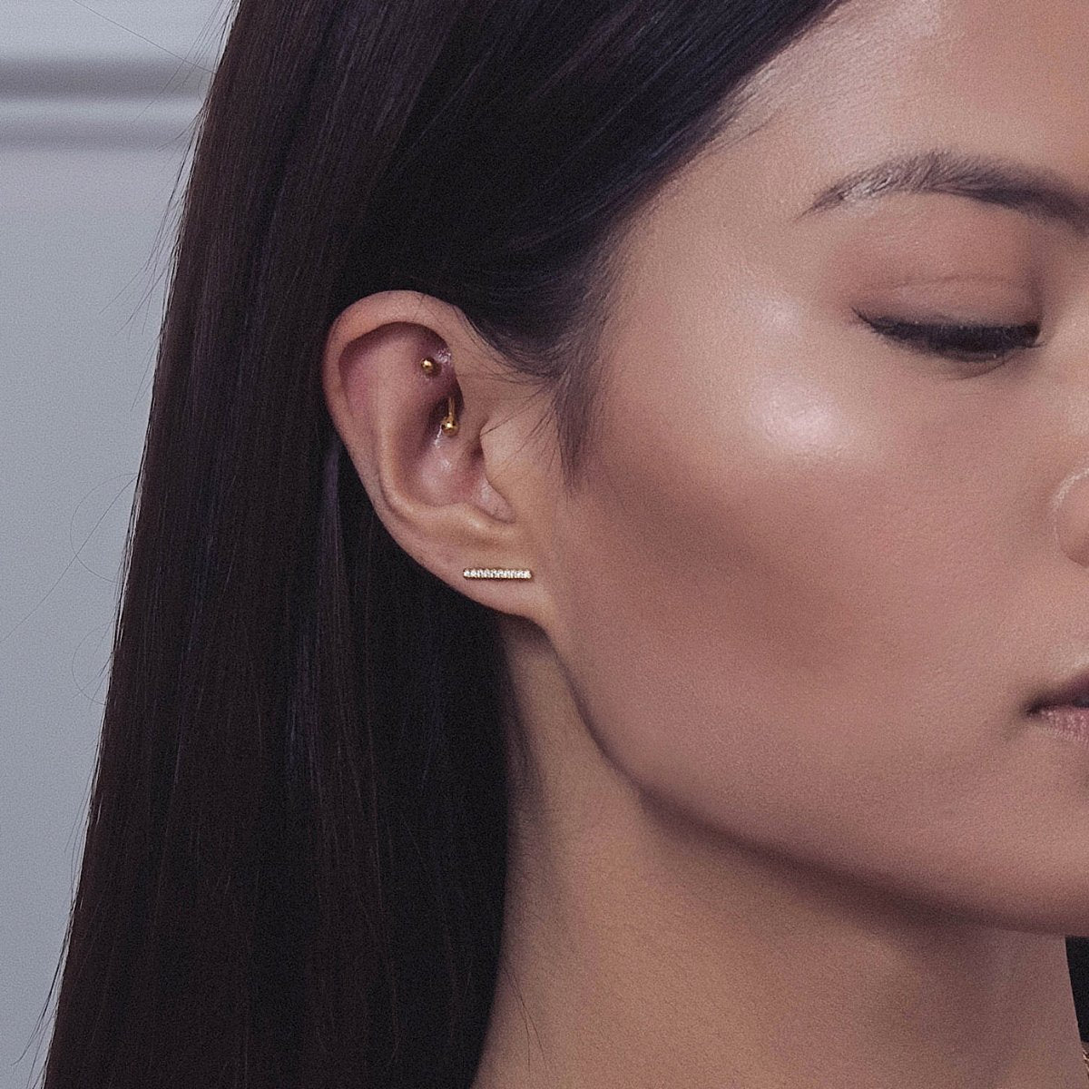 Sterling silver pave bar stud climbing the upper lobe, shown on a model's ear
