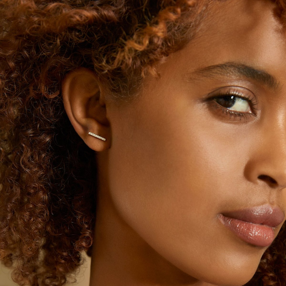 Sterling silver pave bar stud earring with clear stones, shown close-up on a model's upper lobe