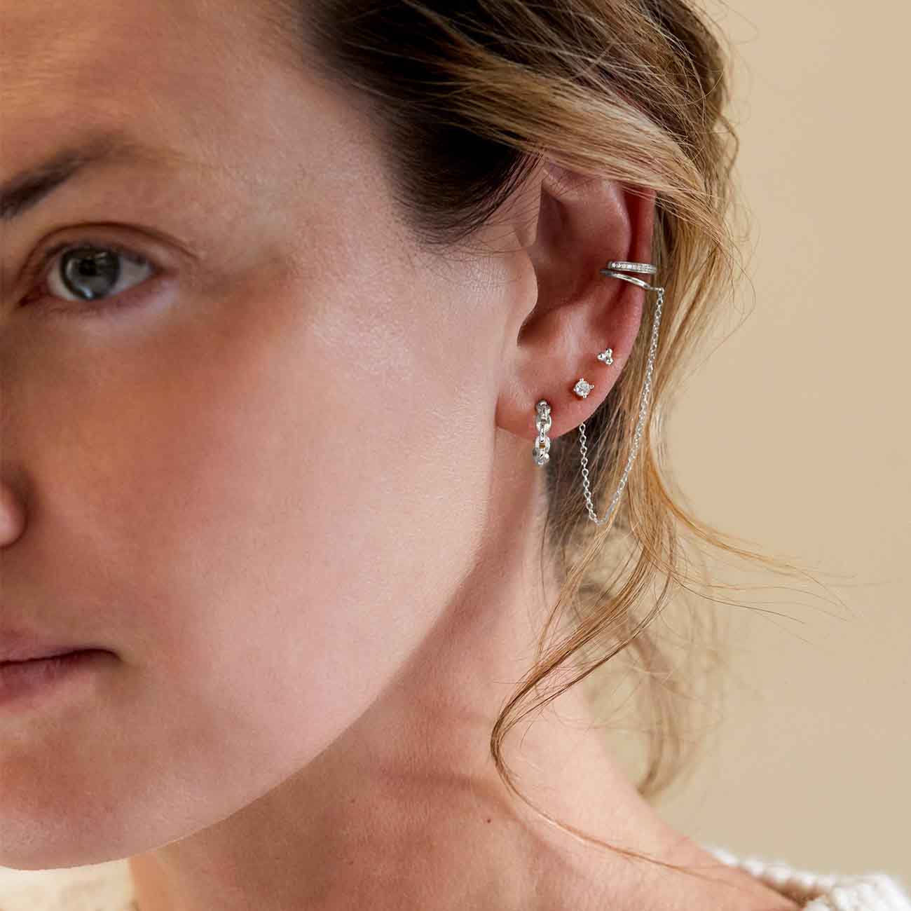 Sterling silver chain-link huggie hoop shown on a model's lobe in an ear stack