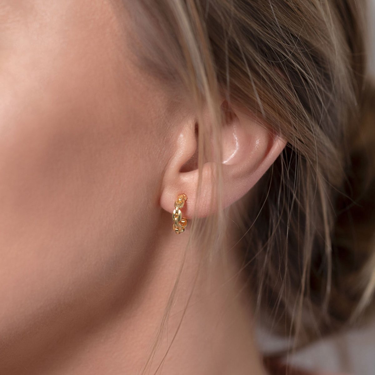 Gold vermeil chain-link huggie hoop shown close-up on a model's lobe