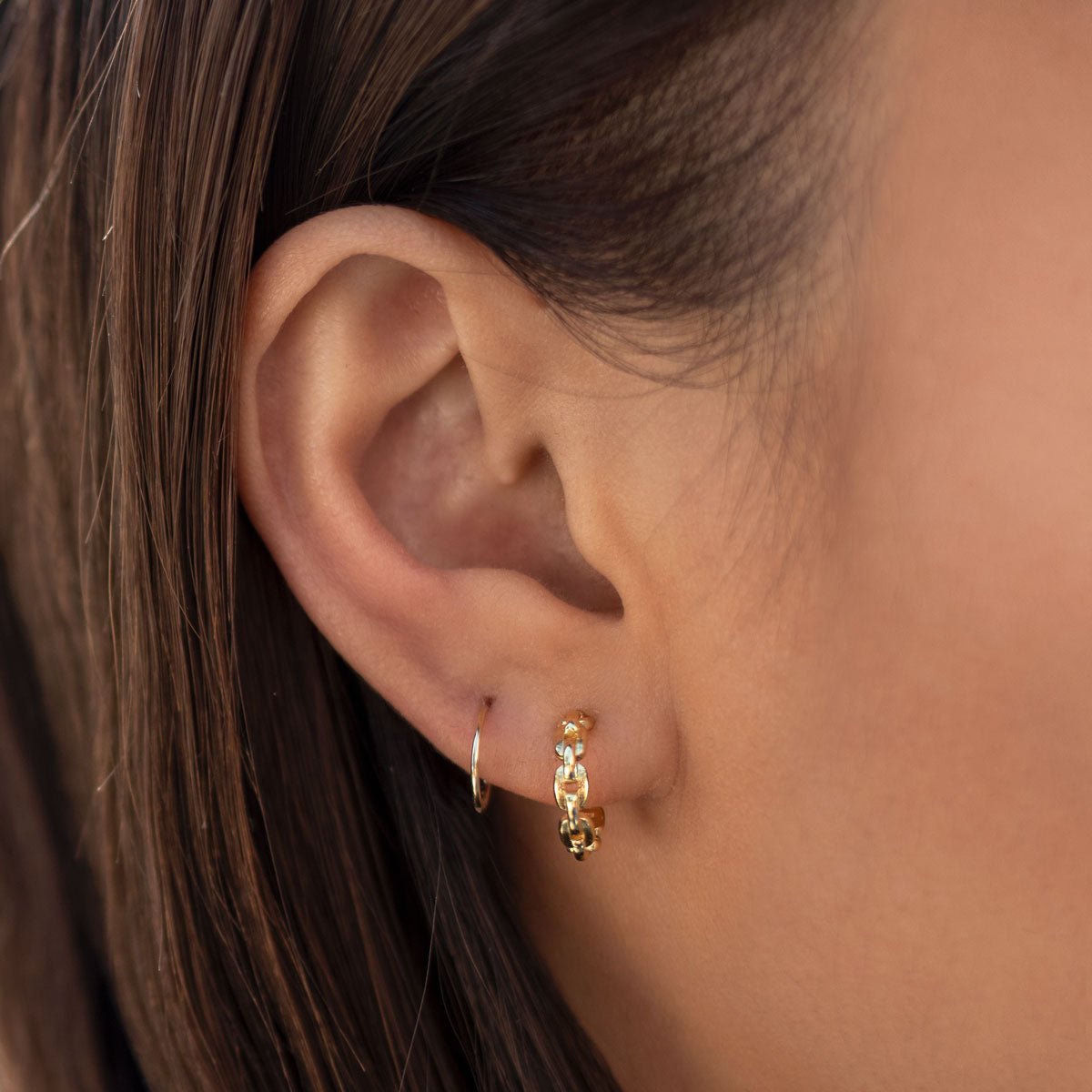 Gold vermeil chain-link huggie hoop shown on a model's lobe beside a thin hoop