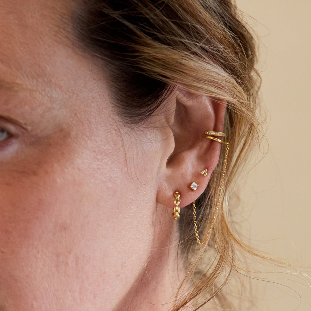 Gold vermeil three-ball cluster stud worn with a chain stud, shown on a model's ear
