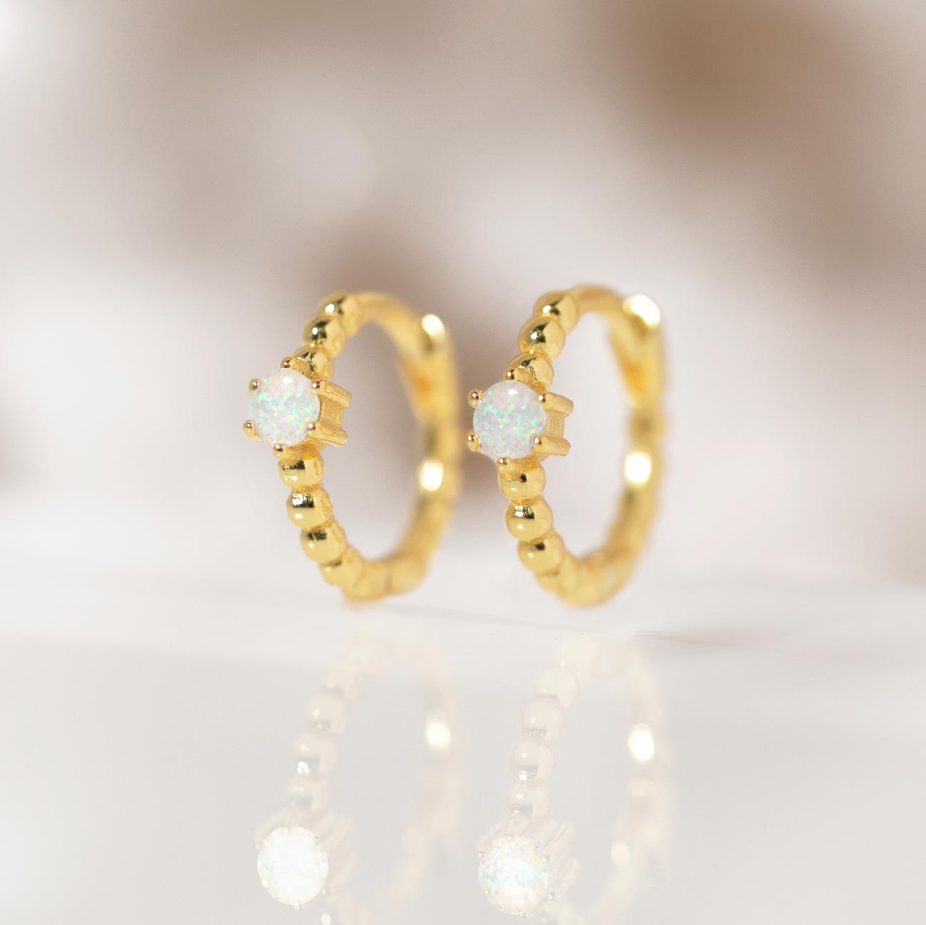 Close-up of earring featuring Gold Vermeil Gemstone Bead Huggies Opal. 