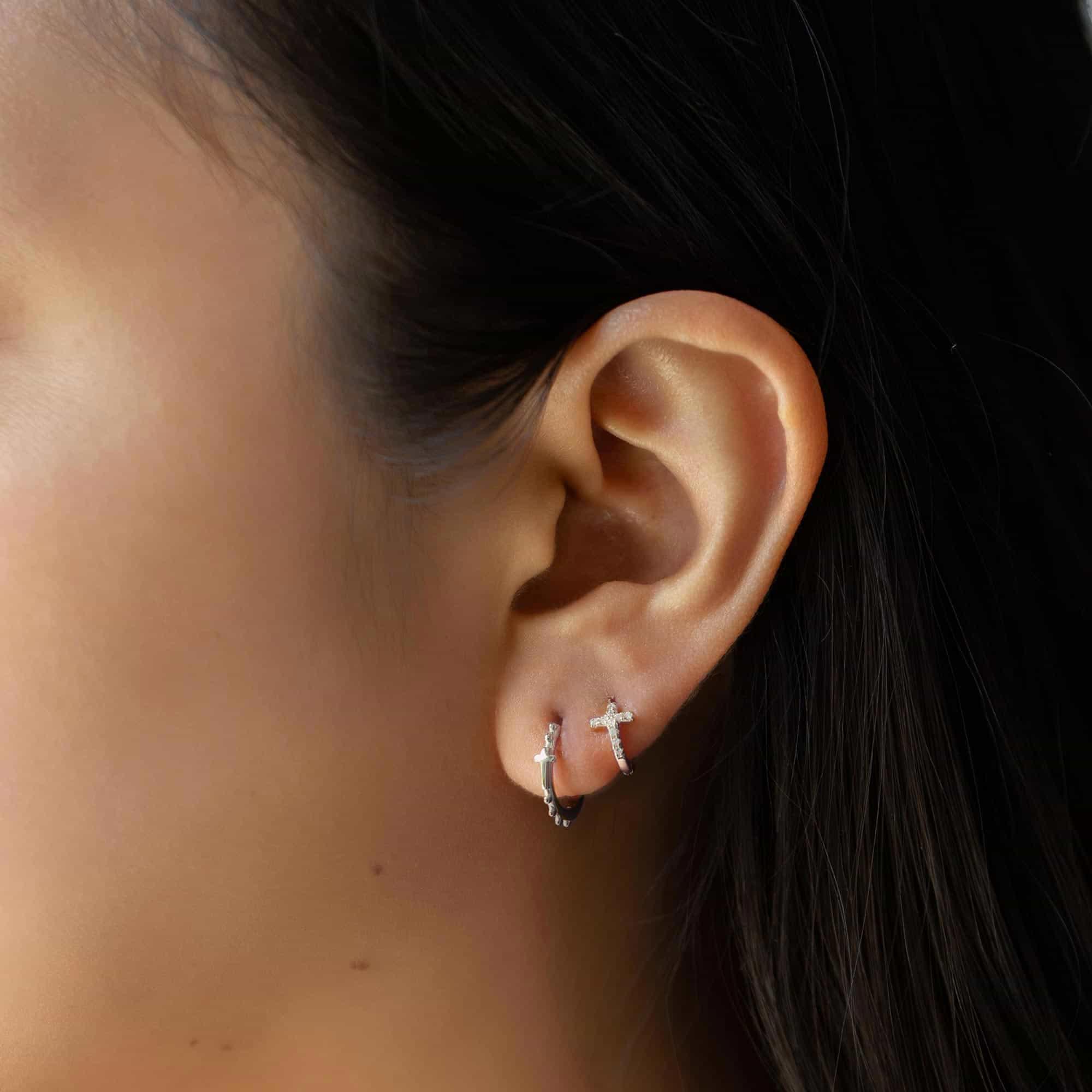 Close-up of a women with gold vermeil tiny cross earrings and cross bead mini hoop earrings. 
