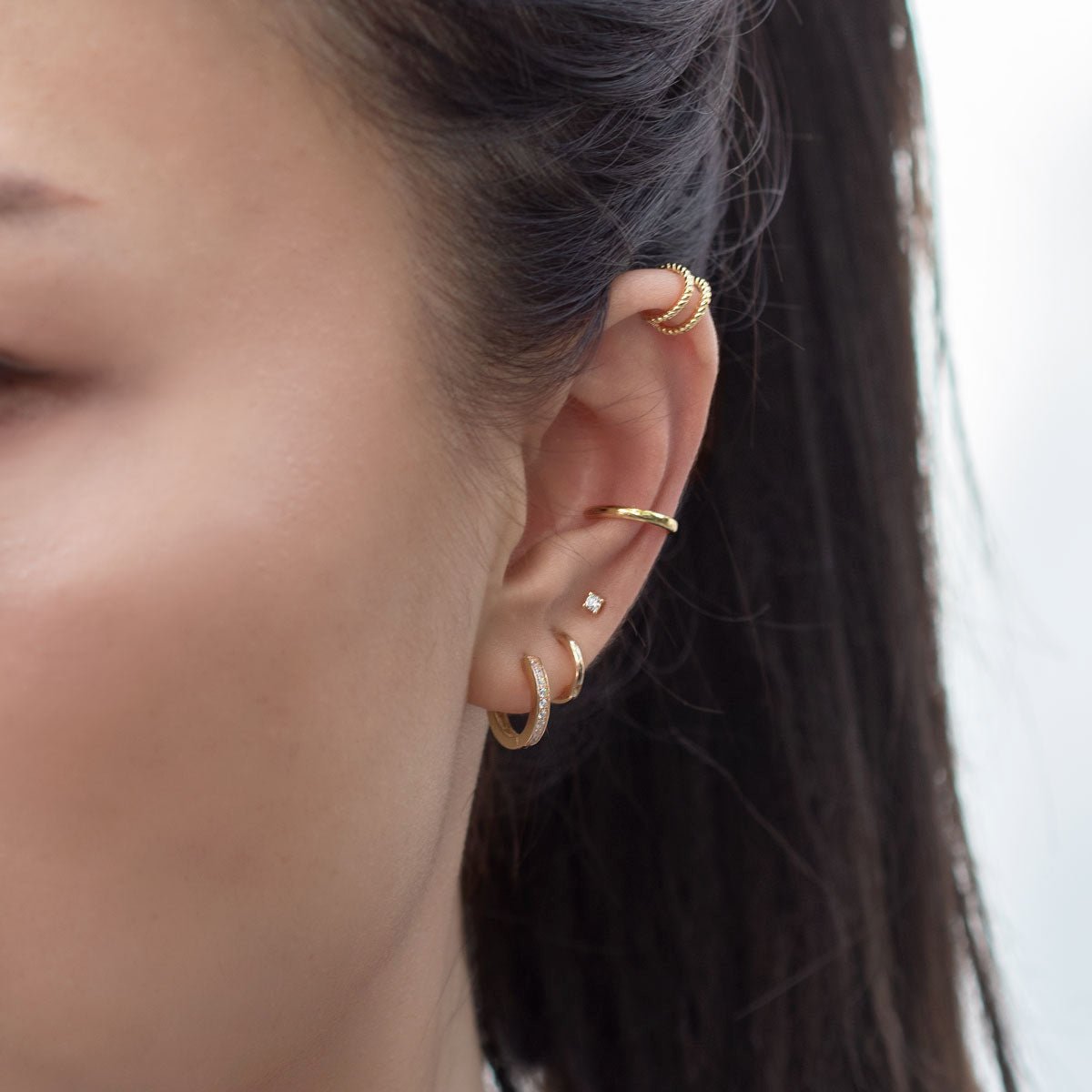 Sterling silver ear cuffs stacked on a model's helix and conch