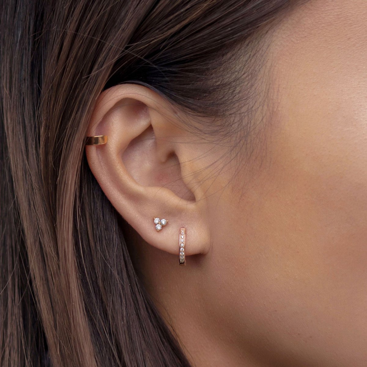 Close up of woman's ear featuring 14K Rose Gold Tiny Clover Pave Stud and huggie earring 