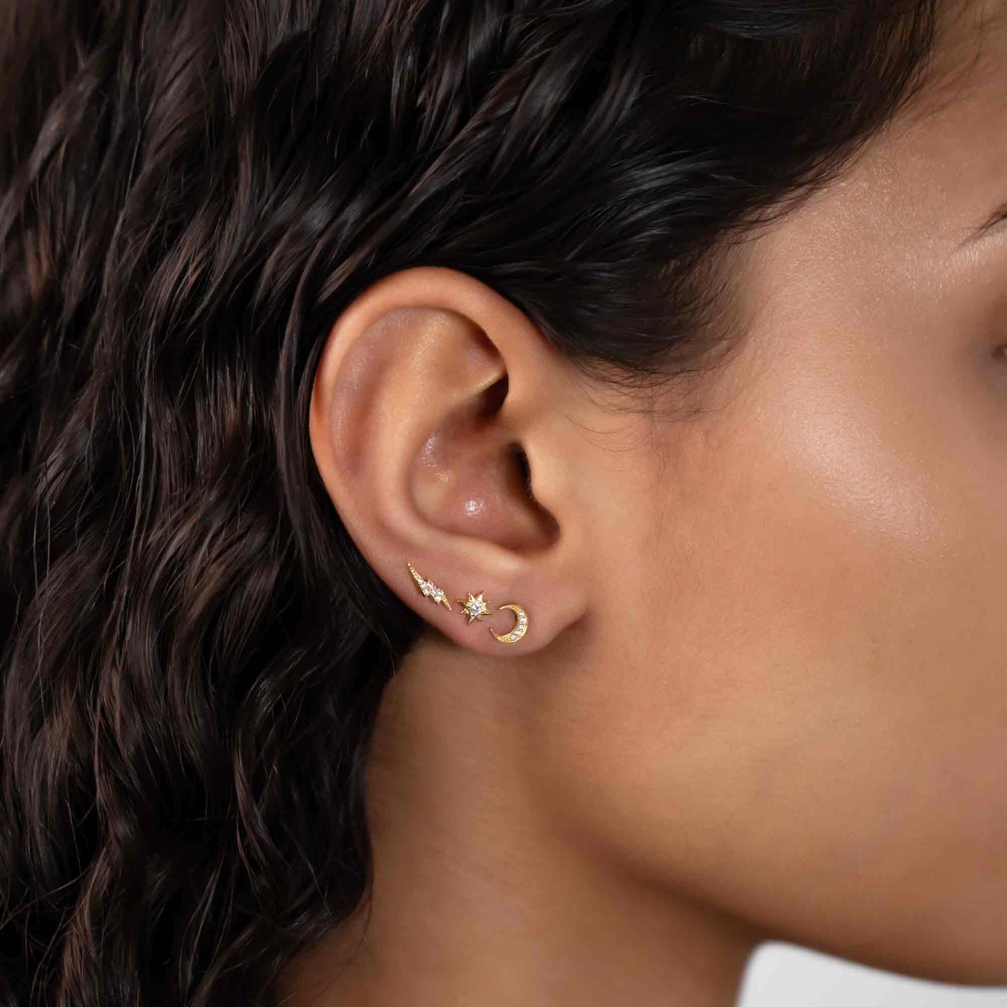 Gold vermeil crescent moon stud with white zirconia, styled with star studs on a model