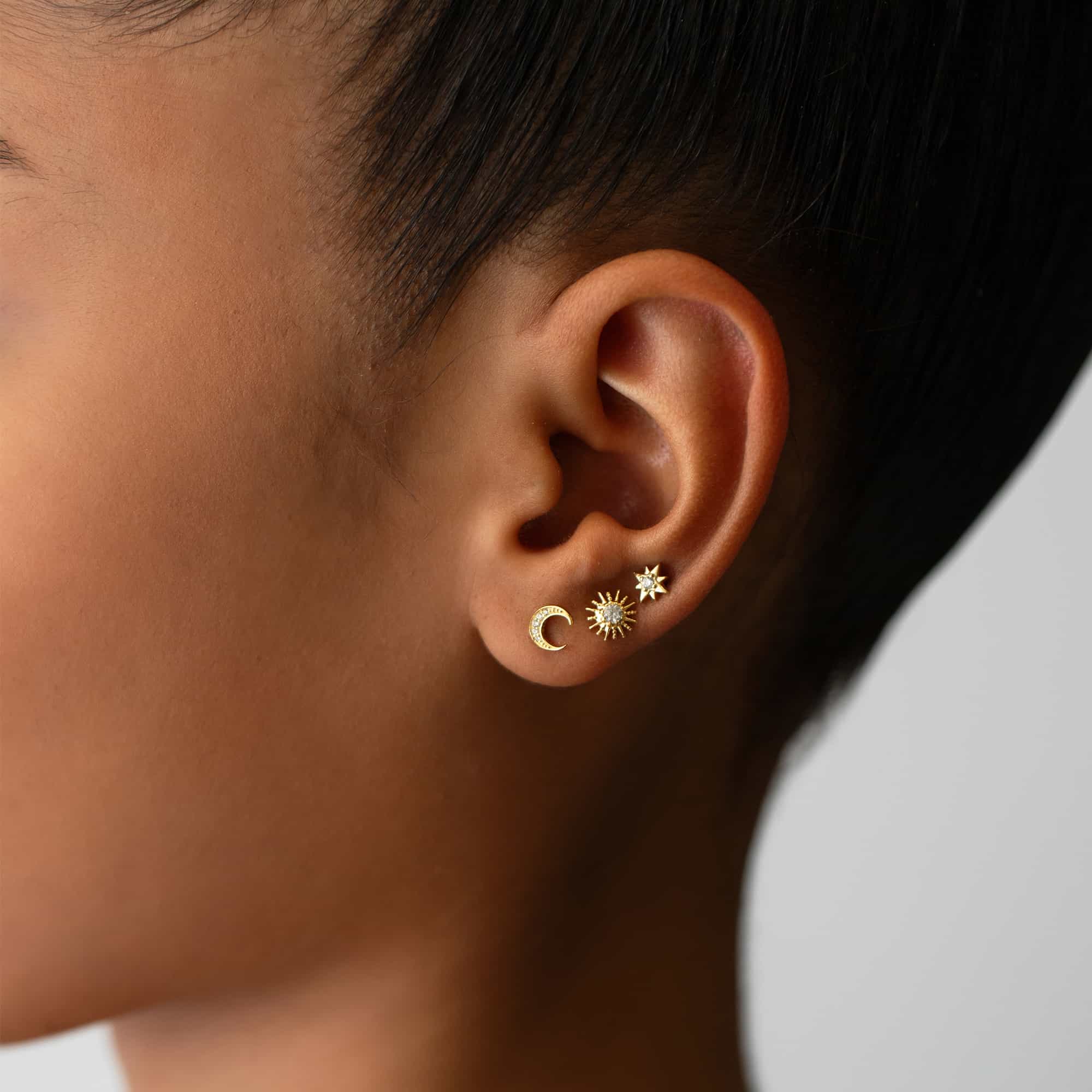 Gold vermeil sunburst stud with a clear stone, shown on a model's lobe in a moon and star ear stack