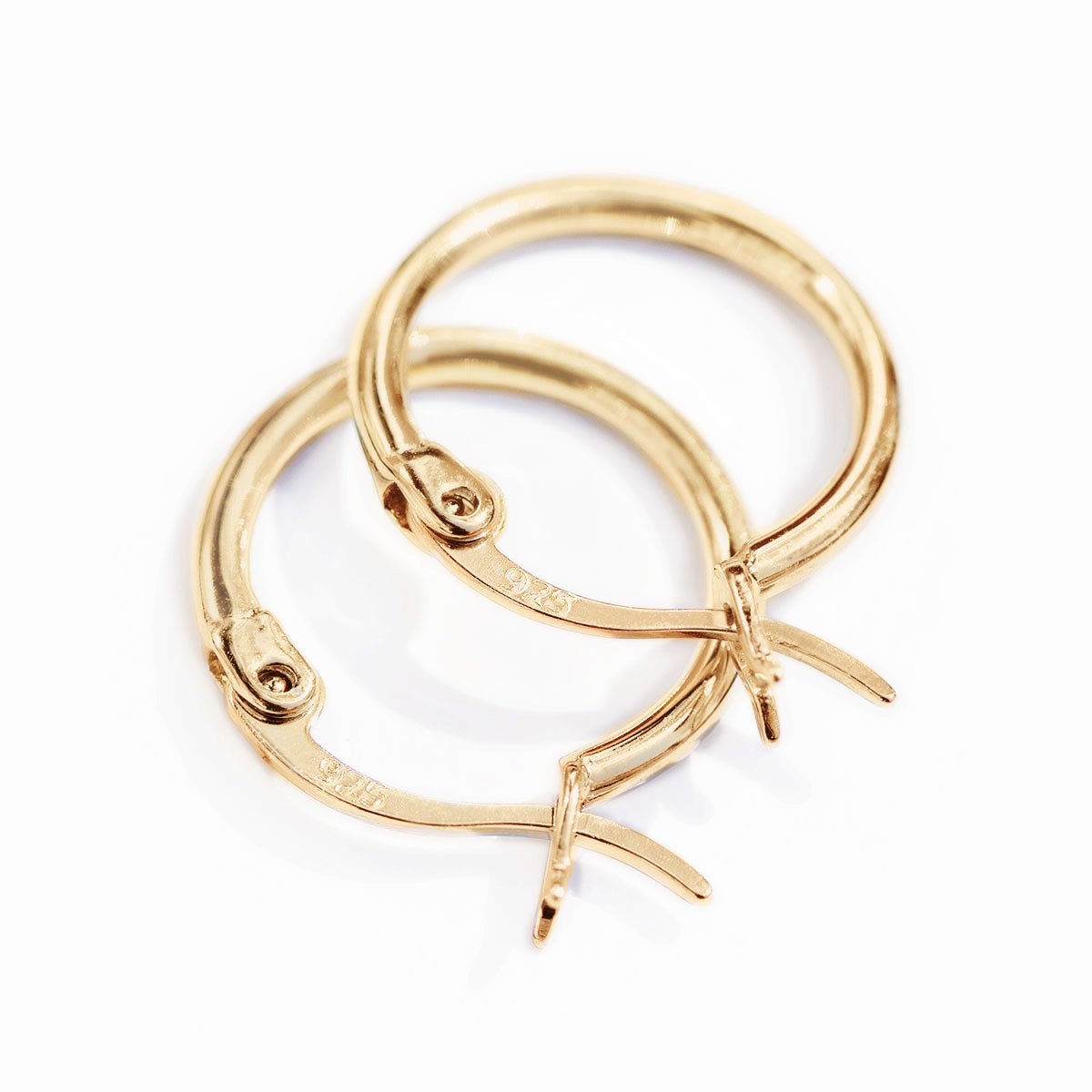 Close-up of gold vermeil small hoop earrings showing the hinged latch closures, on a white background