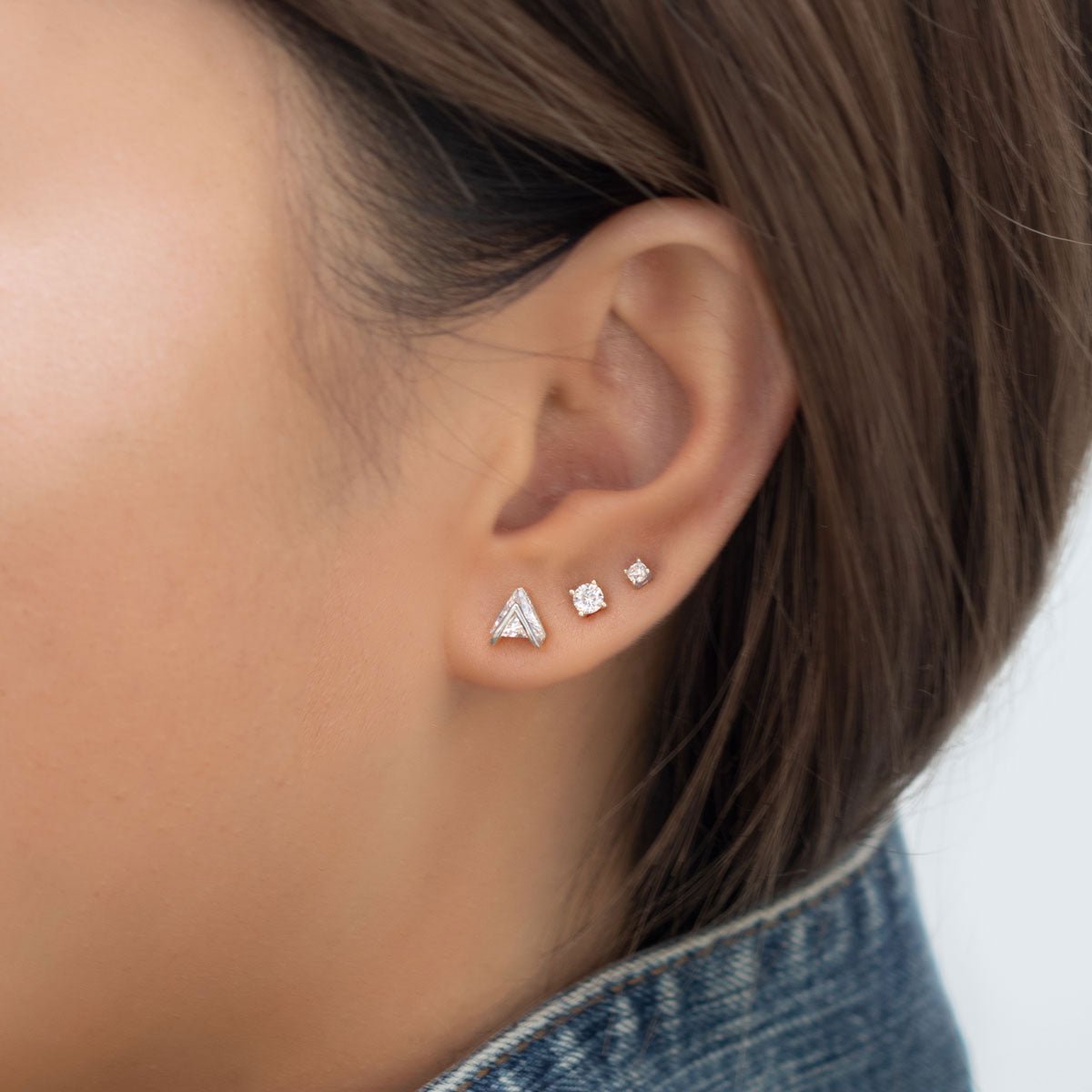 Sterling silver crystal studs set shown on a model's lobe with a chevron and round clear stones
