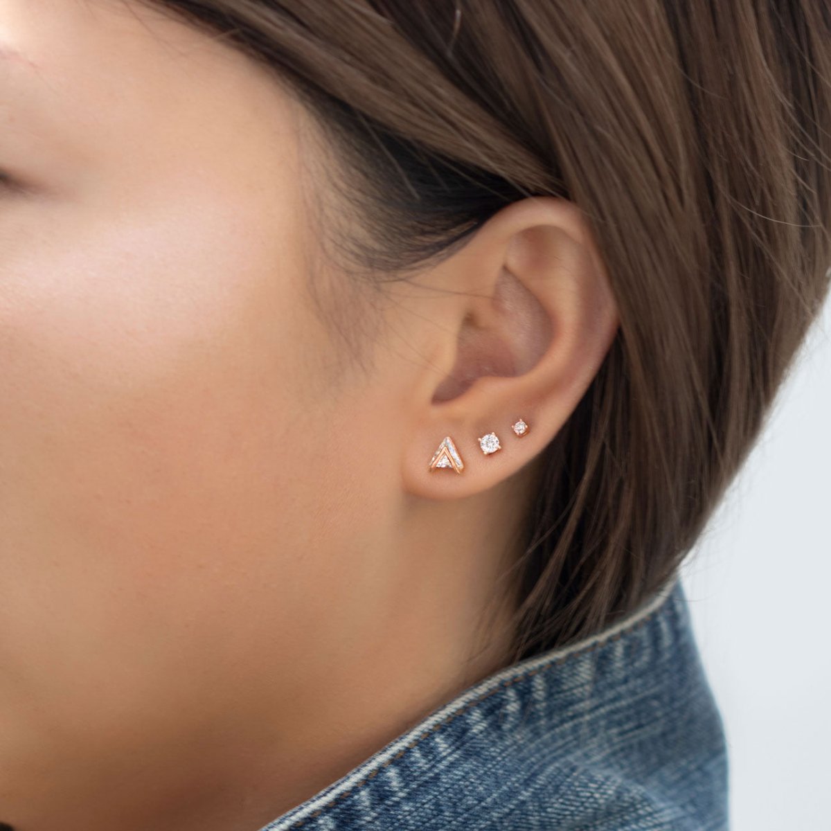 Rose gold vermeil crystal studs set shown on a model's lobe with a chevron and round clear stones