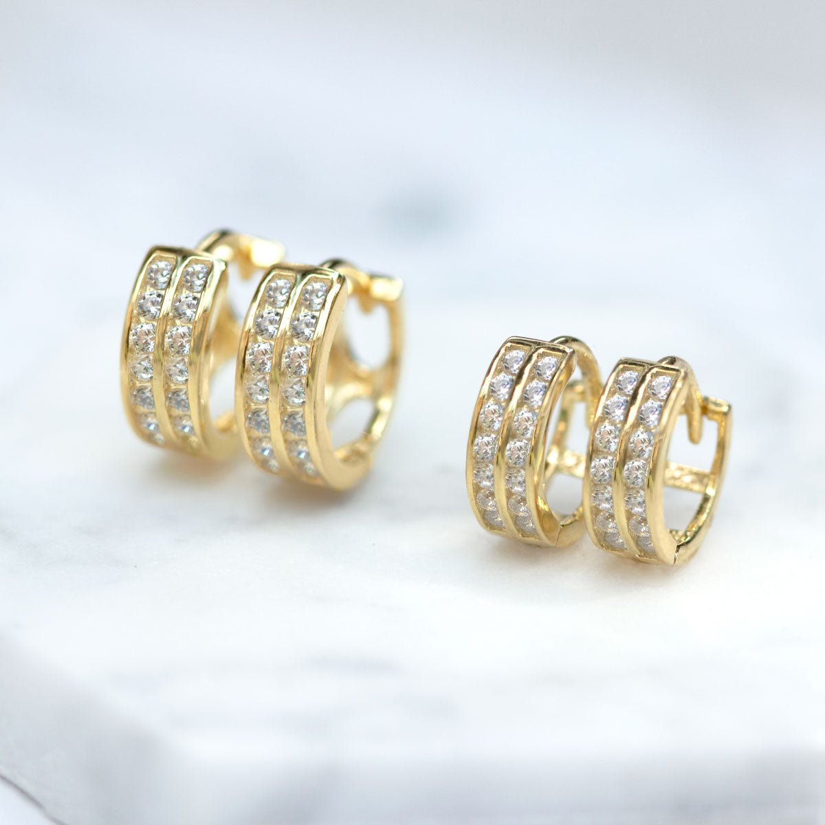 Gold vermeil double row pavé huggie hoops with clear stones, close-up detail on white marble