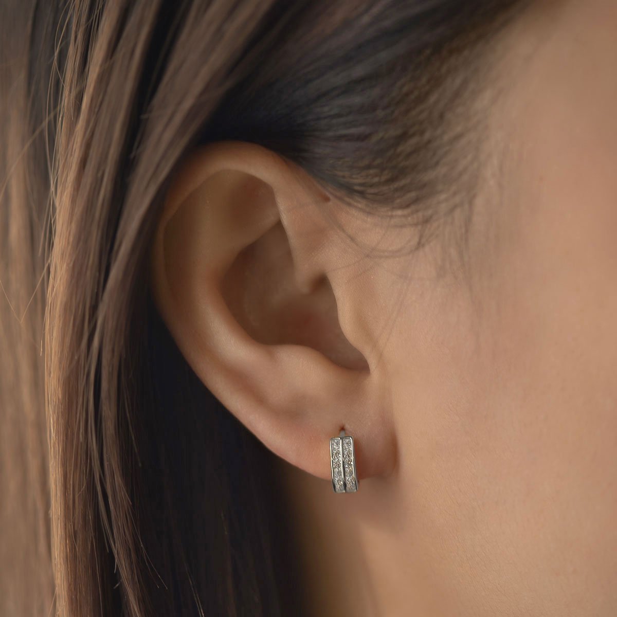 Sterling silver double row pavé huggie hoop with clear stones, shown on a model's lobe