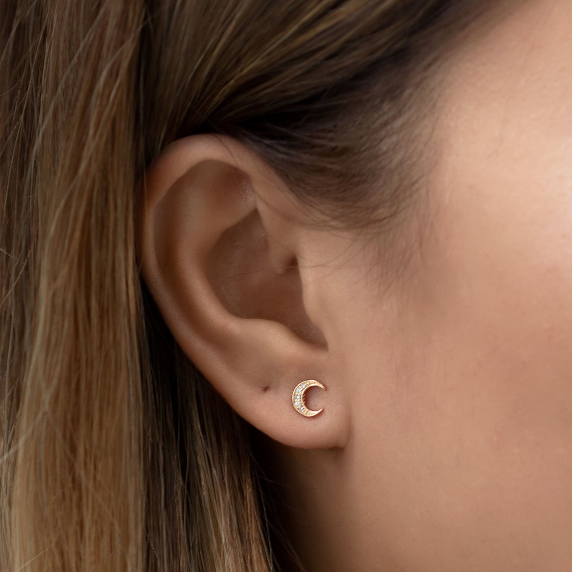 Rose gold vermeil crescent moon stud with white zirconia, shown on a model's lobe