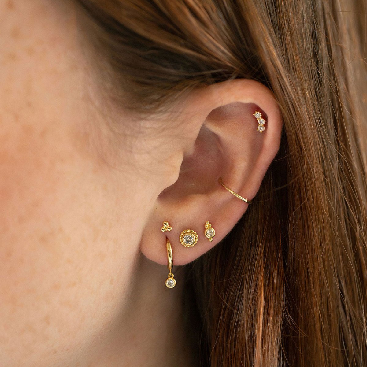 Gold vermeil huggie hoop with a dangling white zirconia drop, styled in an ear stack
