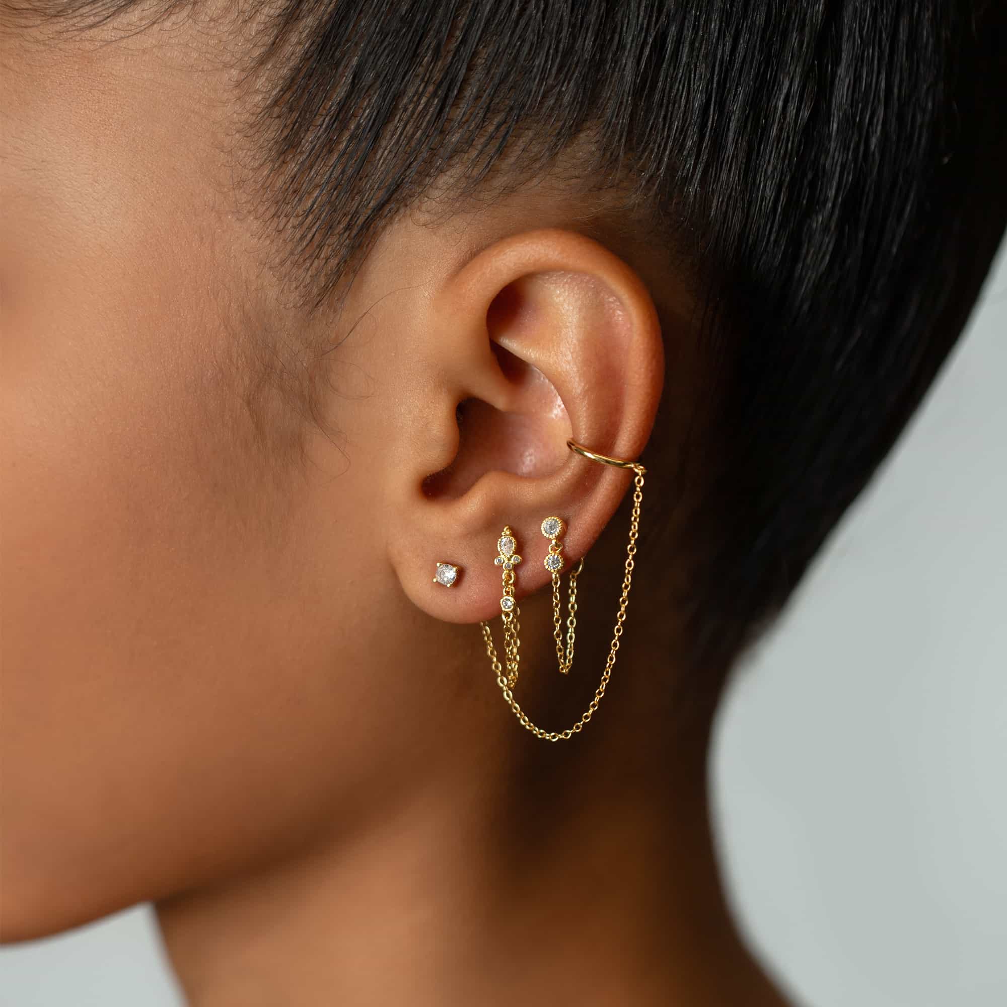 Gold vermeil double bezel chain earrings with white zirconia studs and a draped chain, shown on a model's ear