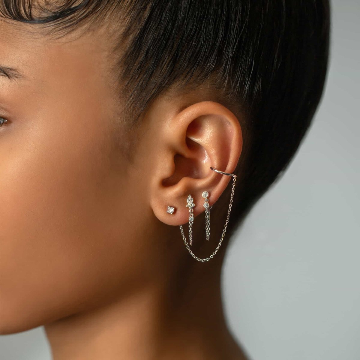 Sterling silver white zirconia chain-wrap stud earring, shown on a model's ear in a stack