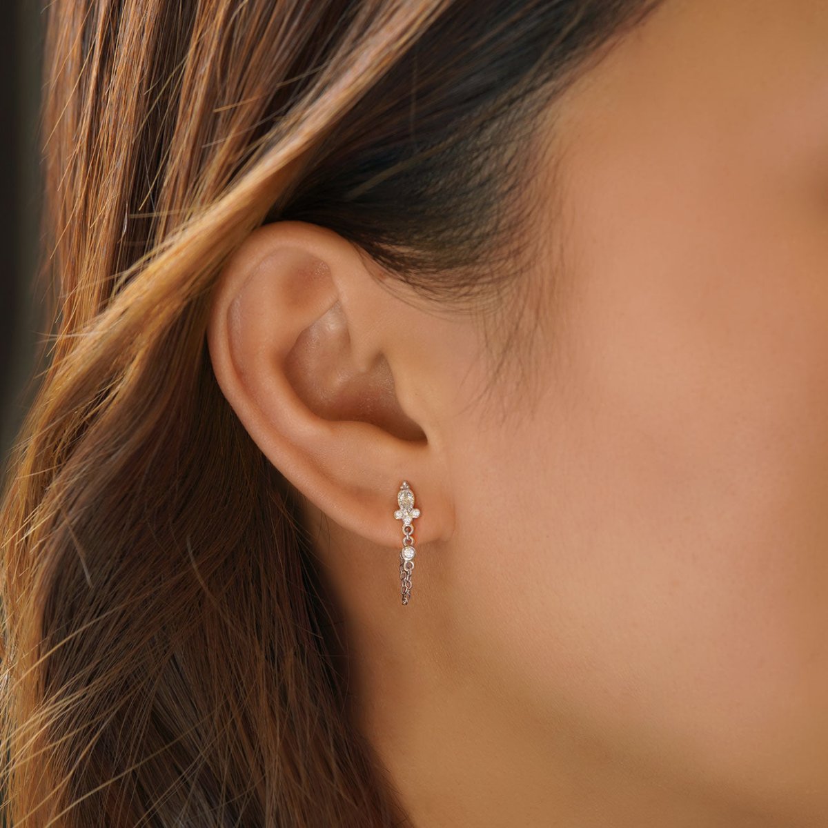 Sterling silver chain stud earring with clear stones, draped chain on a model's side profile