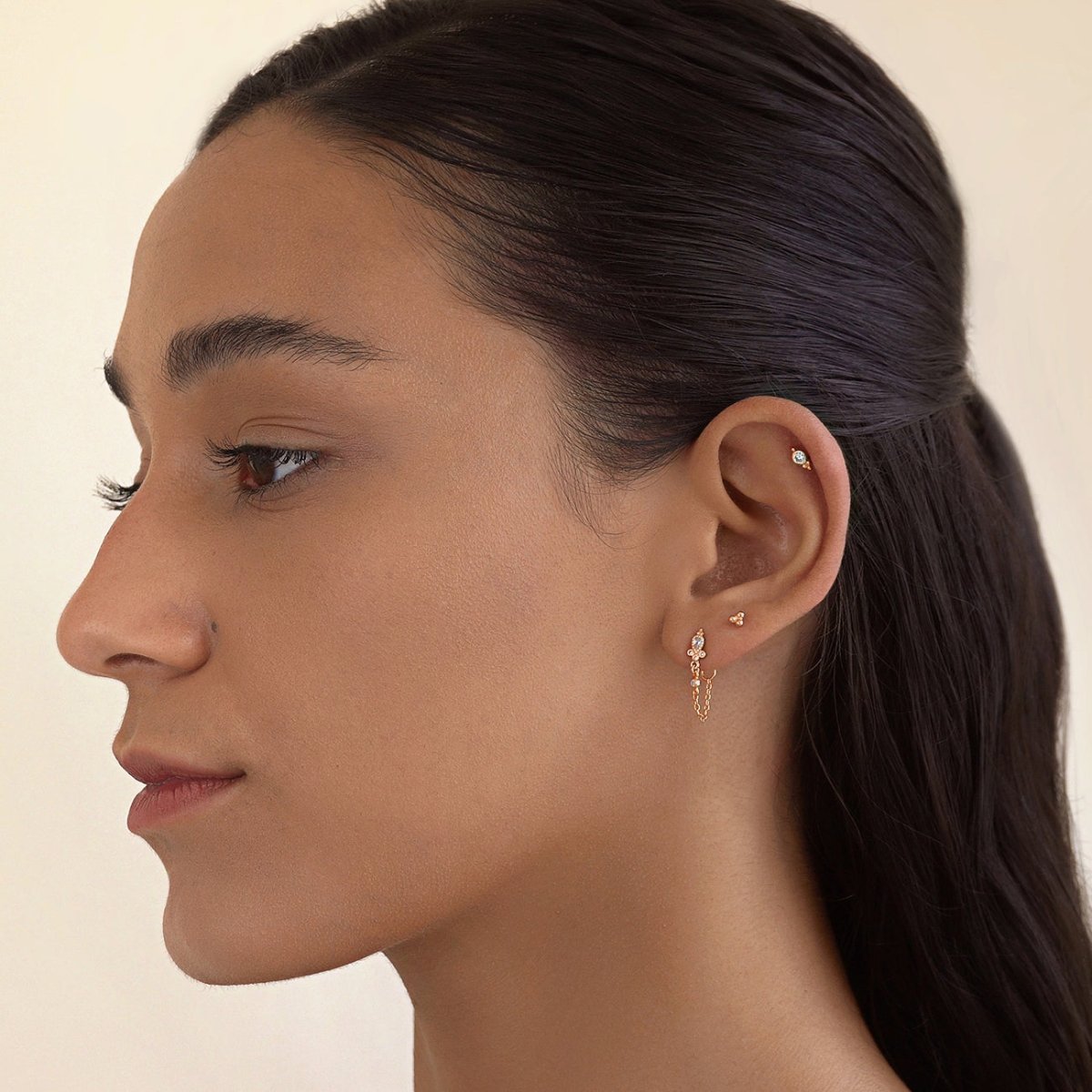 Rose gold vermeil chain stud earring with clear stones and a draped chain, shown on a model's ear