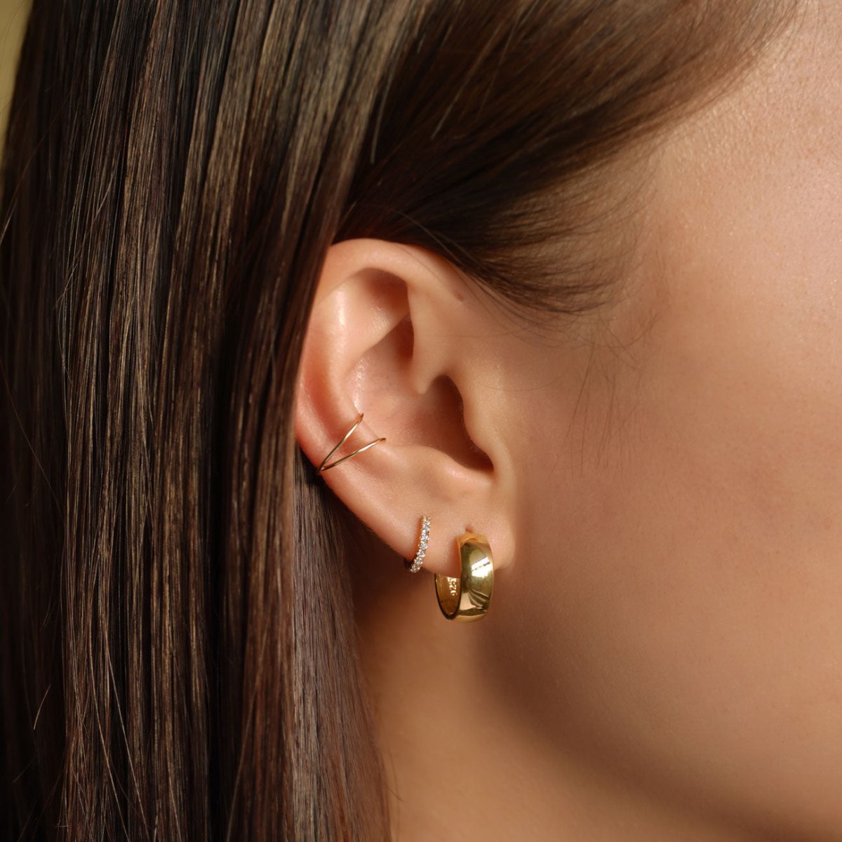 Gold chunky huggie hoop stacked with a slim pavé hoop, shown on a model's lobe